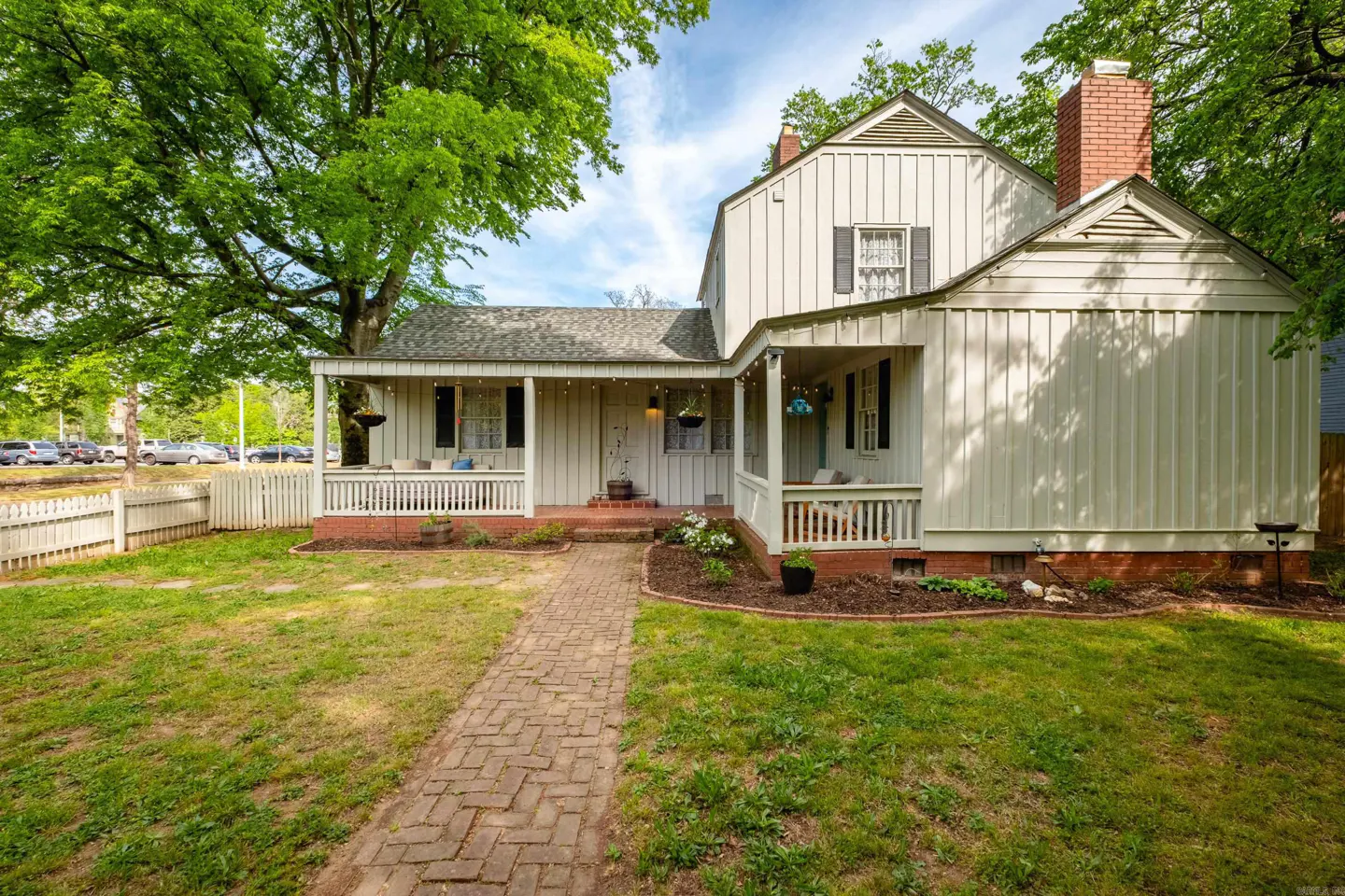 Exterior view of a two-story white house with a brick chimney, a brick walkway, and a green lawn.
