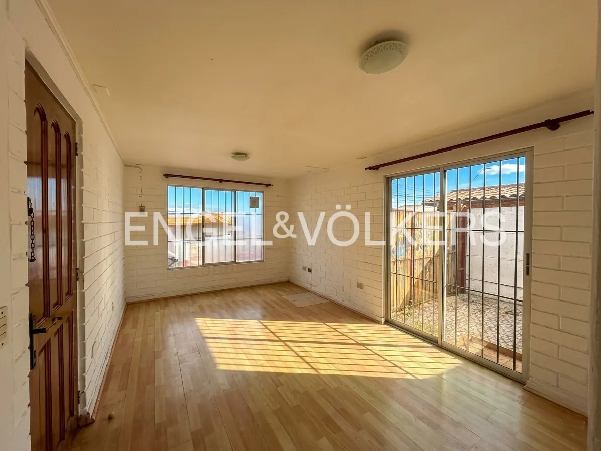 Bright, empty room with wood floors, white brick walls, and sliding glass doors to a patio. A wooden door is on the left.