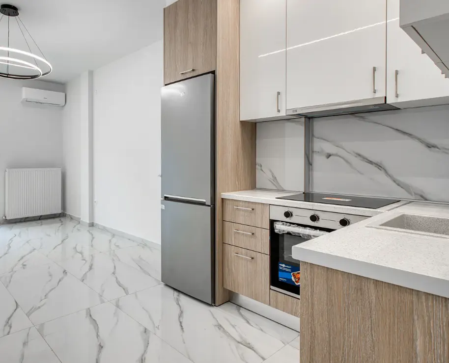 A modern kitchen with white cabinets, a stainless steel refrigerator, and marble floors.