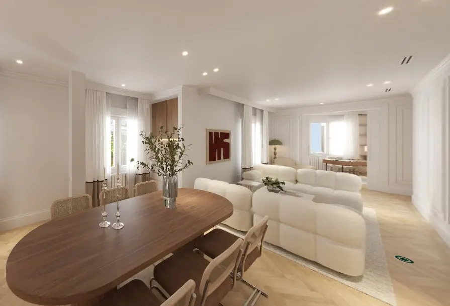 Bright, open-concept living and dining area with a wood table, white sofa, and herringbone floors. A vase of greenery sits on the table.