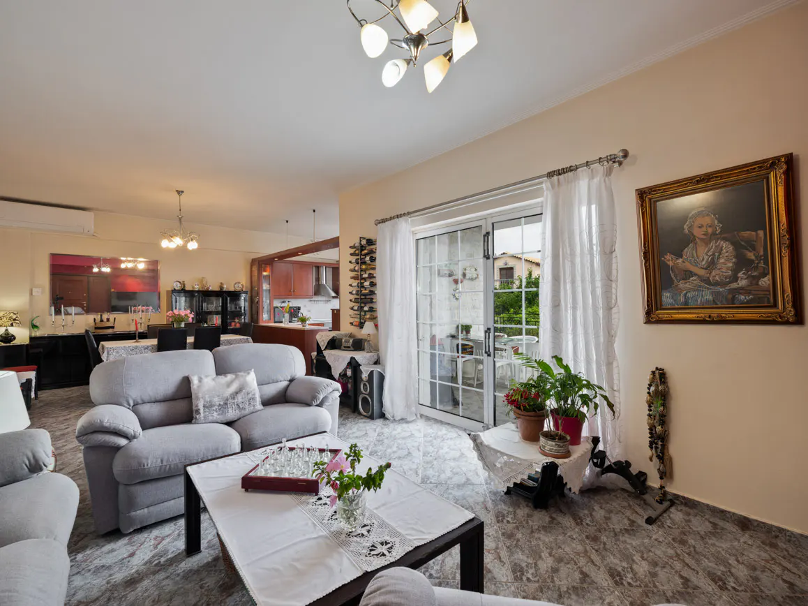 Spacious living room with a grey sofa, coffee table, glass sliding doors to a patio, and a framed portrait on the wall.