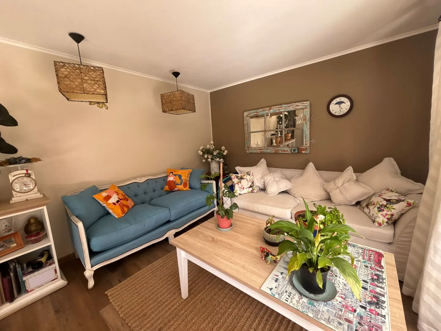 Living room with a blue sofa, a white sofa, a wooden table, and two wicker lamps.