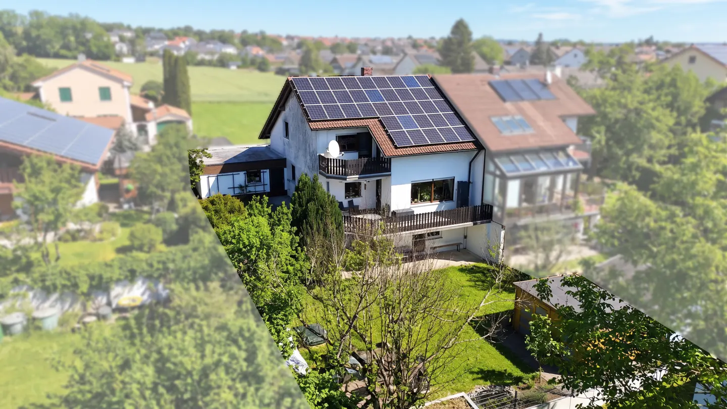 Aerial view of a two-story white house with solar panels on the roof, surrounded by green trees and a lawn.