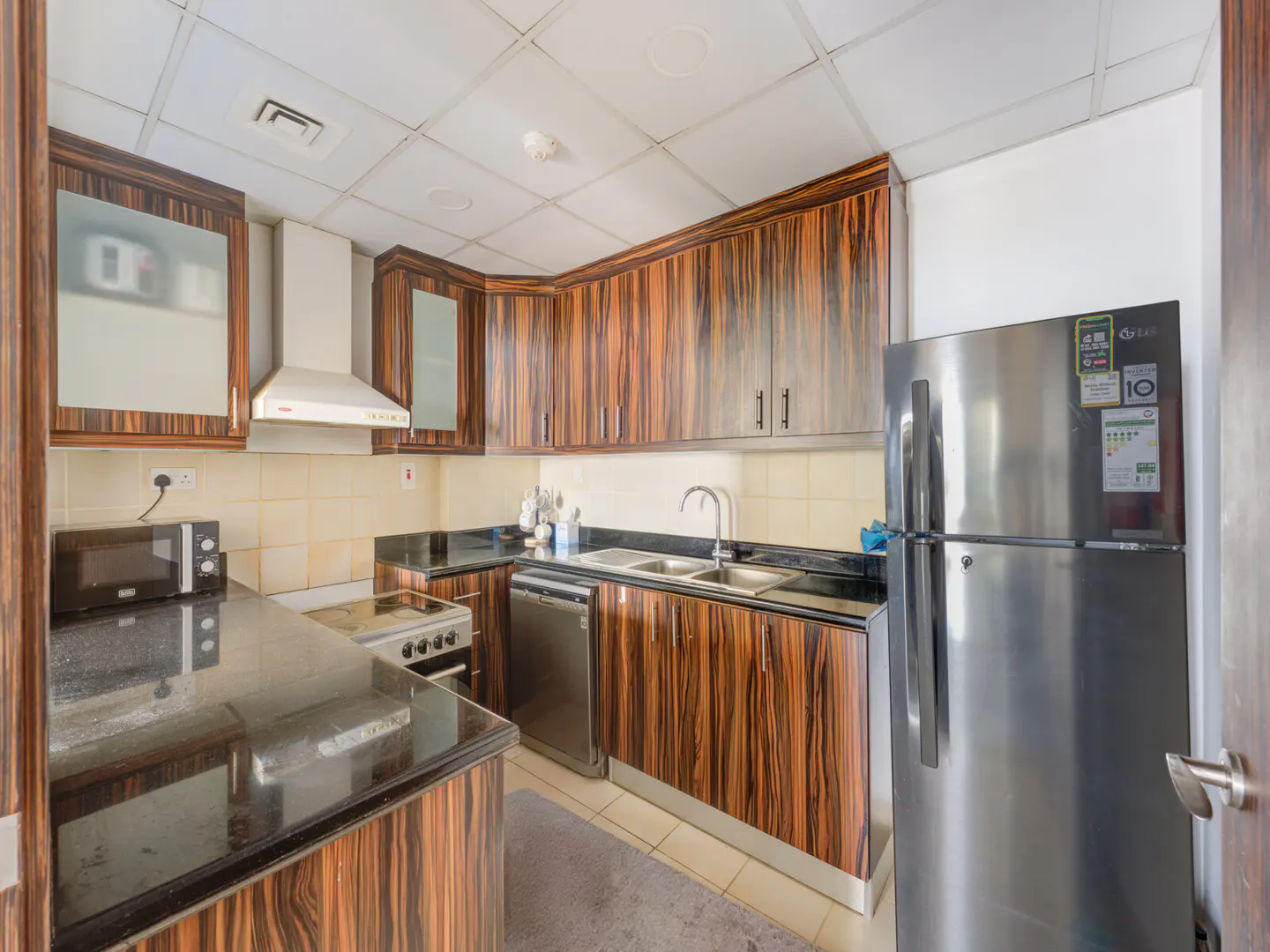 A kitchen with wood-grain cabinets, black countertops, and stainless steel appliances.
