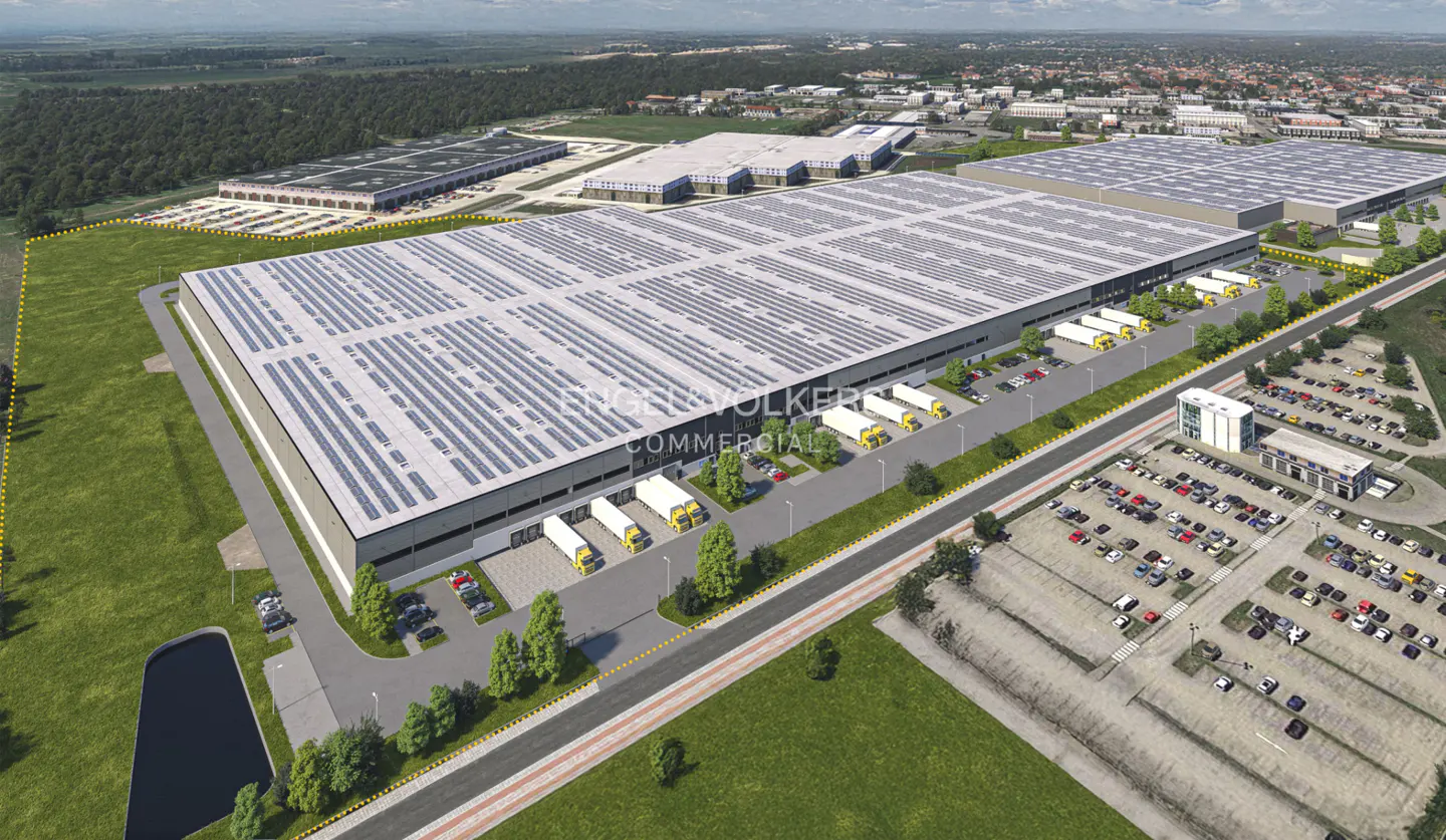 Aerial view of a large industrial warehouse complex with solar panels on the roof, loading docks, and a parking lot.