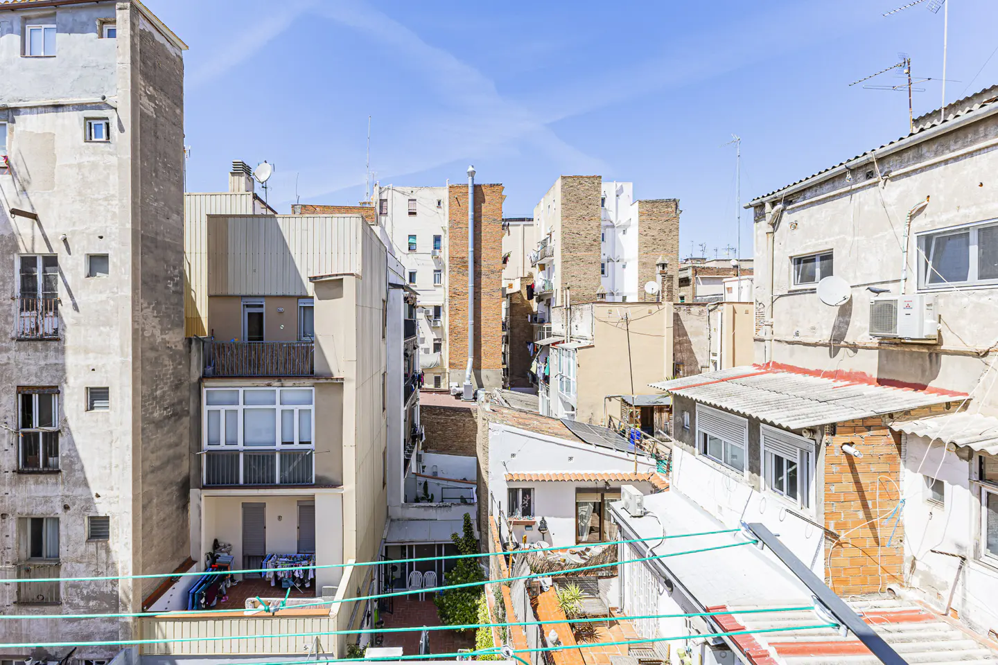 View of a dense urban neighborhood with buildings of varying heights and colors under a blue sky.