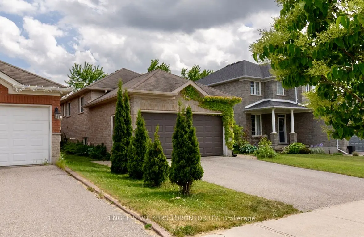 A suburban street view of a tan brick house with a brown double garage, green trees, and cloudy sky.