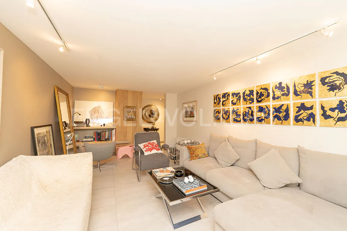 A living room with beige walls, a gray sofa, and a black coffee table. Art hangs on the wall.