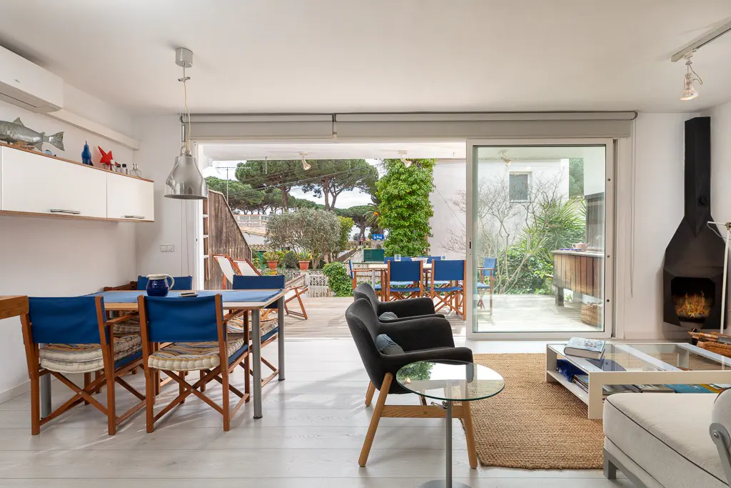 Bright living room with blue dining chairs, black armchairs, a modern fireplace, and sliding doors to a patio.