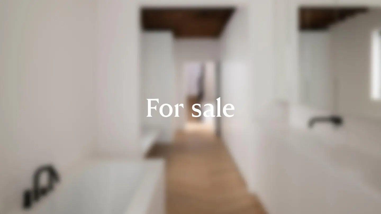 Blurred view of a bright, white bathroom with dark fixtures and the words "For sale" superimposed.