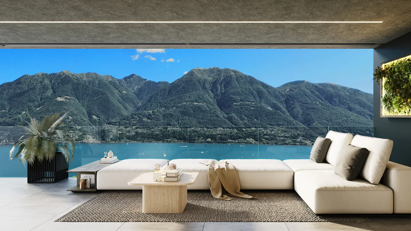 Modern balcony with white sectional sofa, coffee table, and potted plant overlooking a lake and mountain range.