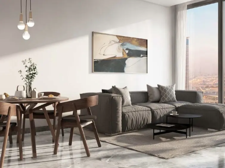 Bright living room with a gray sectional sofa, round wooden table with chairs, and a large window overlooking a city.