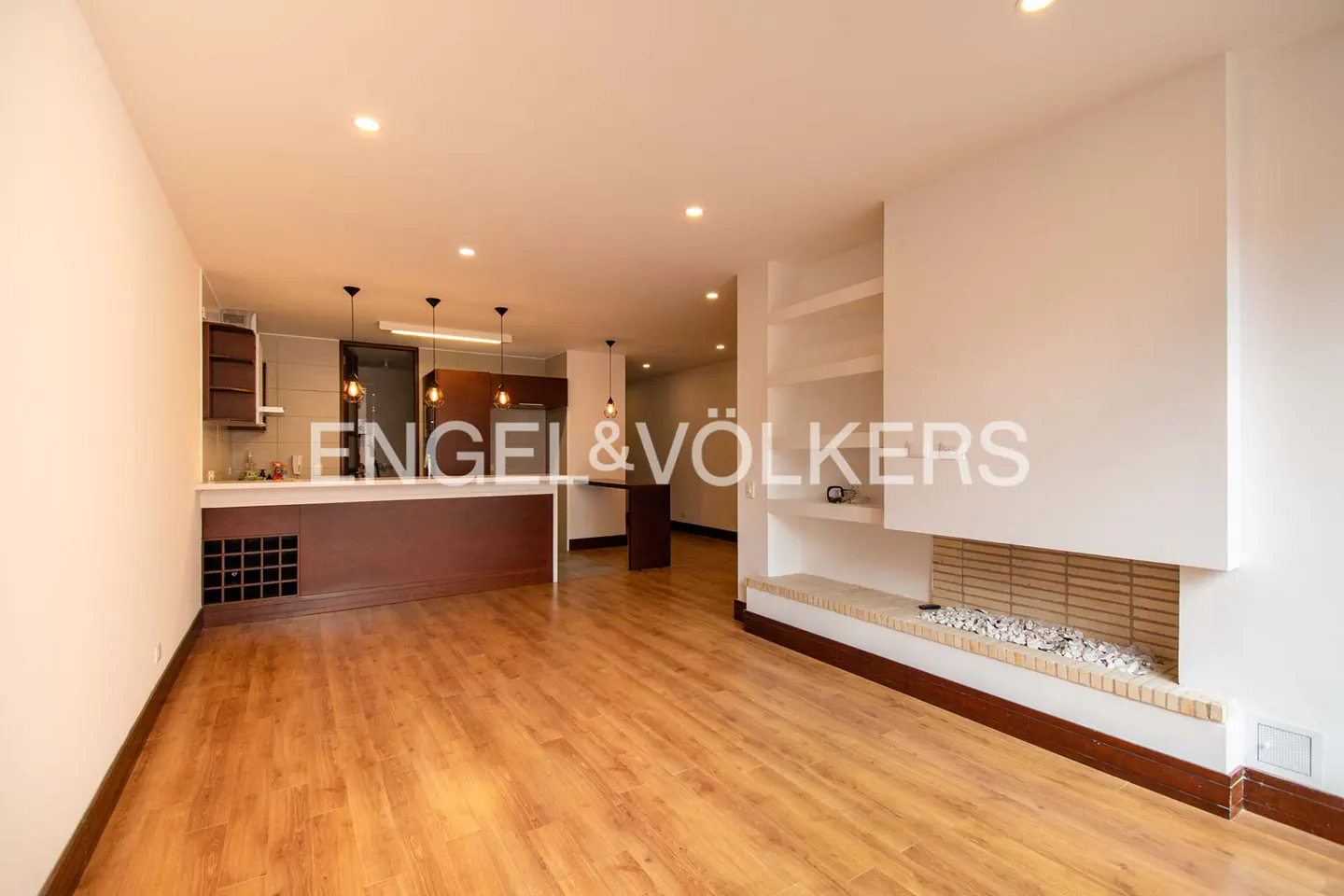 Bright, open-concept living space with wood floors, a kitchen bar, and a modern fireplace with built-in shelving.