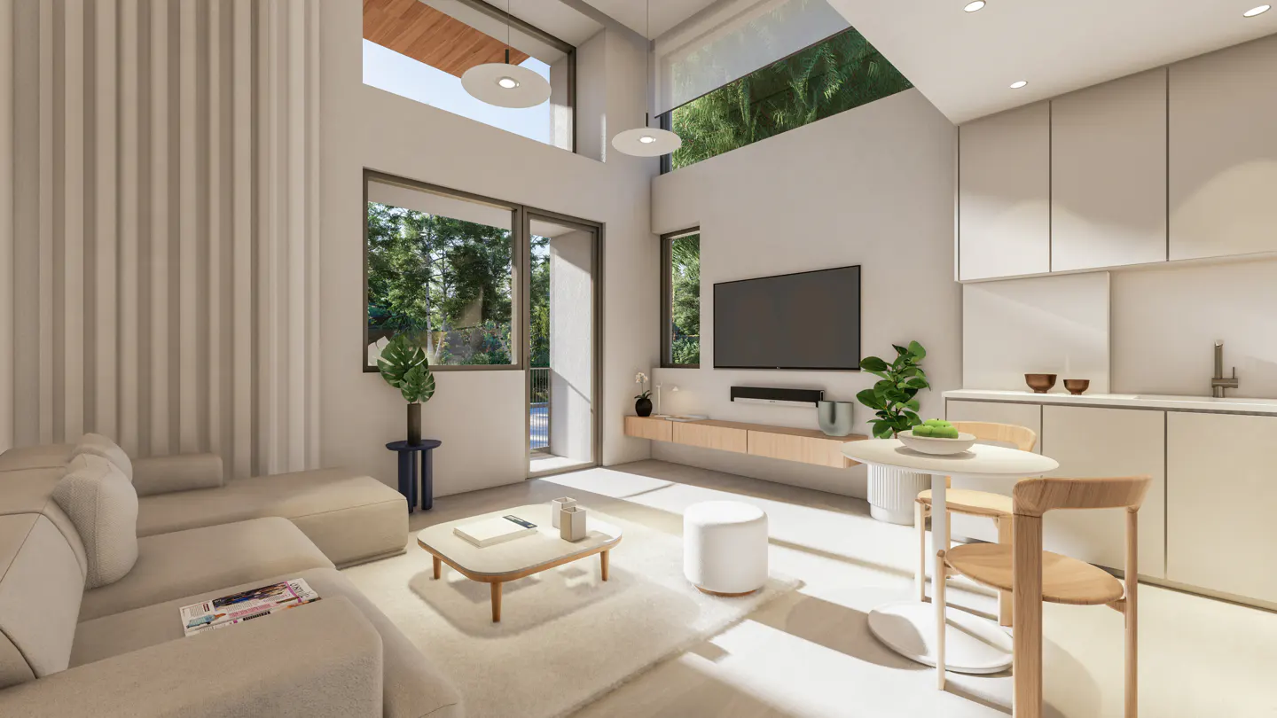 Bright, modern living space with a beige sectional sofa, white rug, and a coffee table. A TV is mounted above a light wood console. Kitchen cabinets are white.