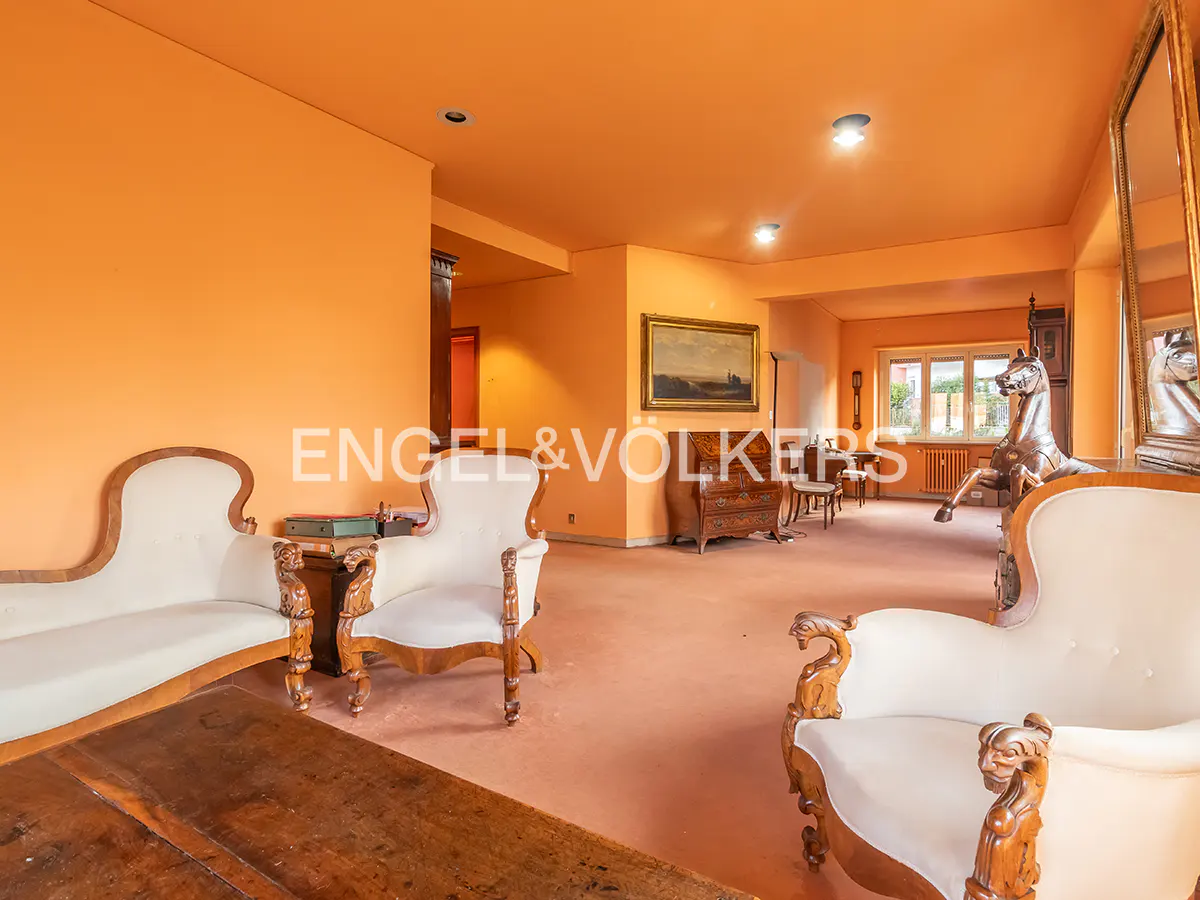 A living room with orange walls, white sofas, and a wooden horse statue.