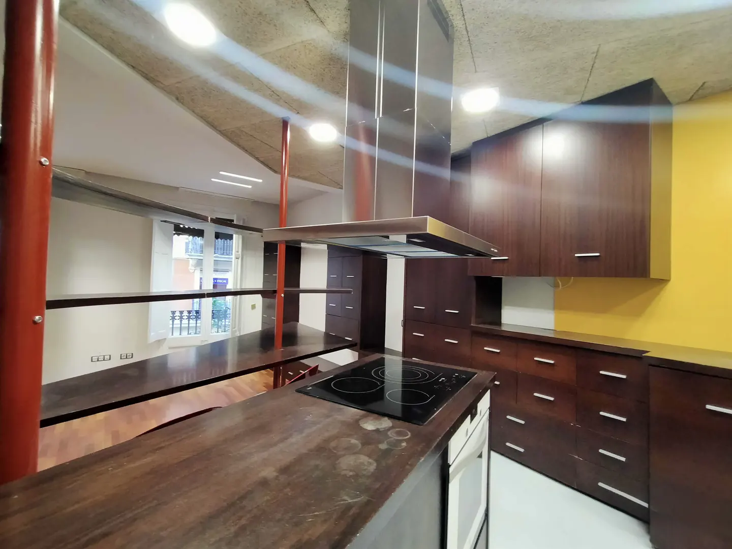 A modern kitchen with dark wood cabinets, a stainless steel range hood, and a dark countertop island with a cooktop.