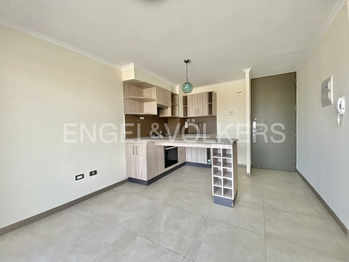 Open-concept kitchen and living area with light wood cabinets, granite countertop, and gray tile flooring.
