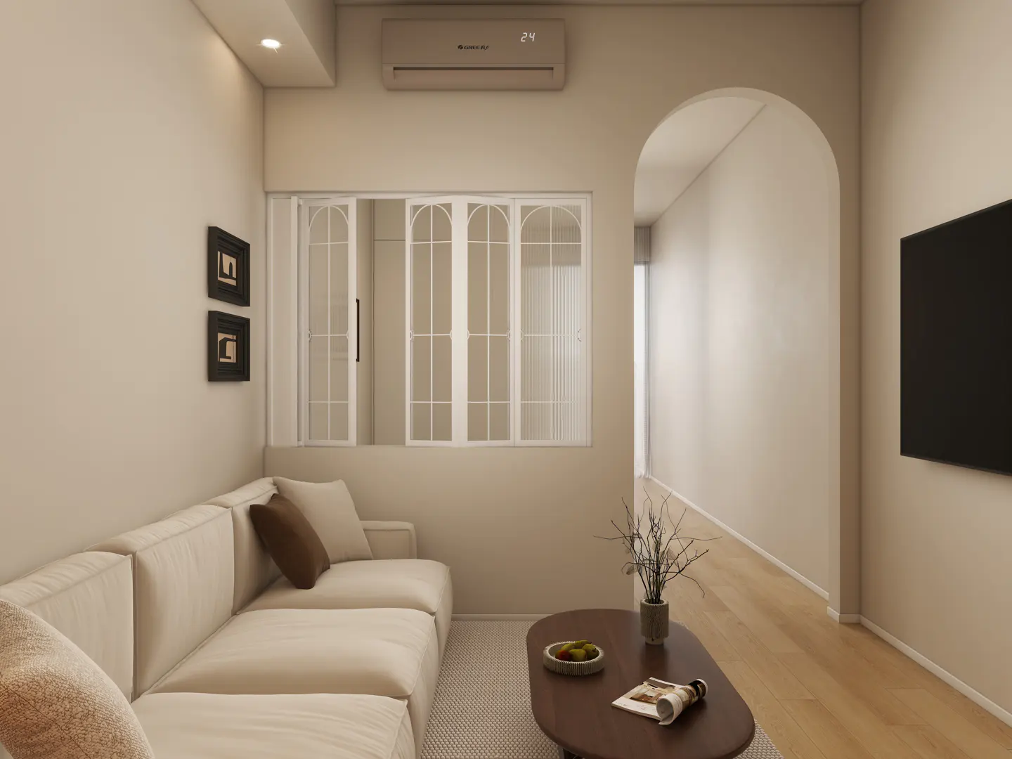 Living room with a cream sofa, brown coffee table, and a black TV on the wall. An arched doorway leads to another room. Two framed pictures hang on the wall.