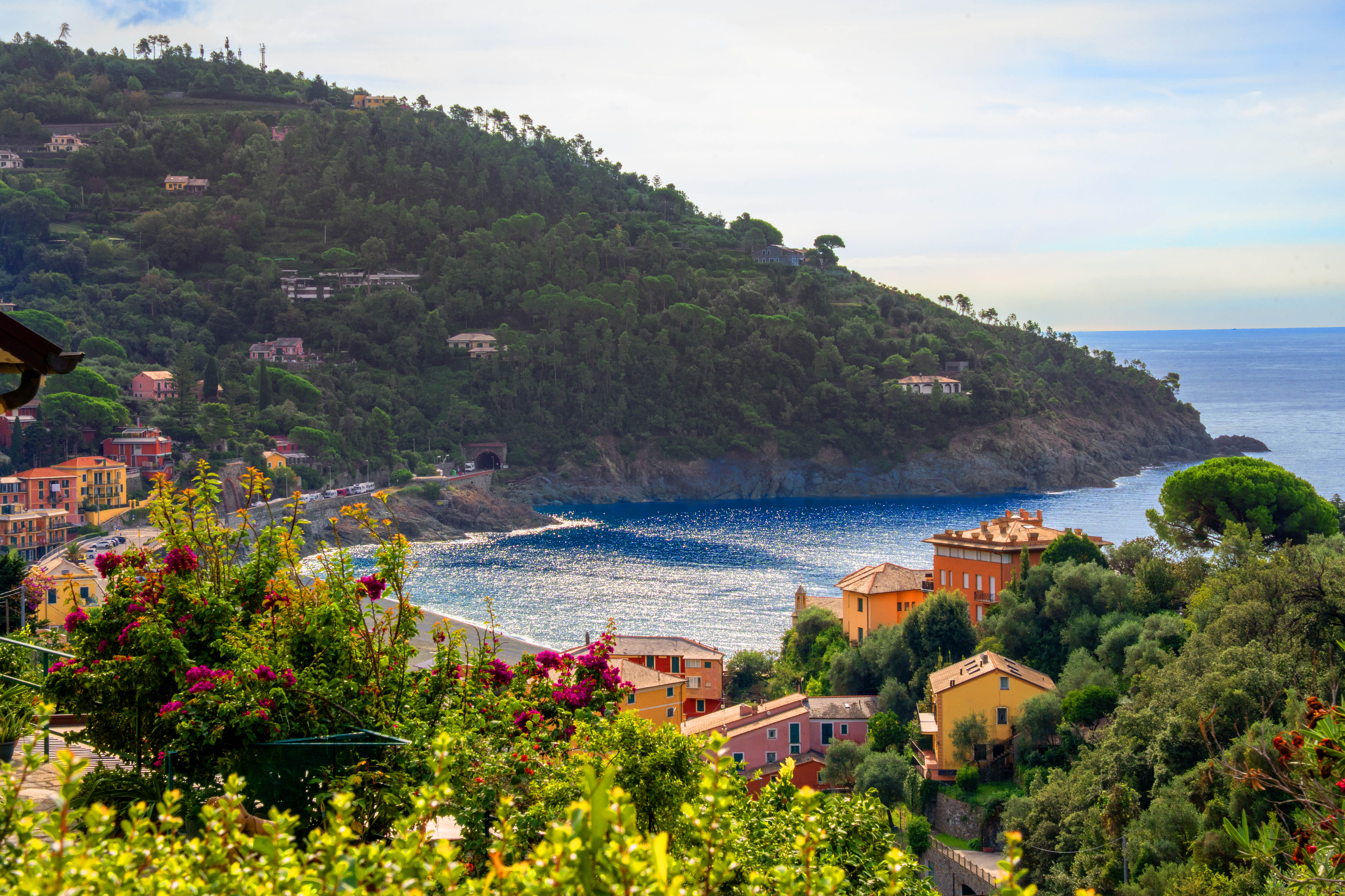 Colorful Mediterranean village nestled on a lush green hillside overlooking a sparkling blue bay and the sea. [AI-generated text]