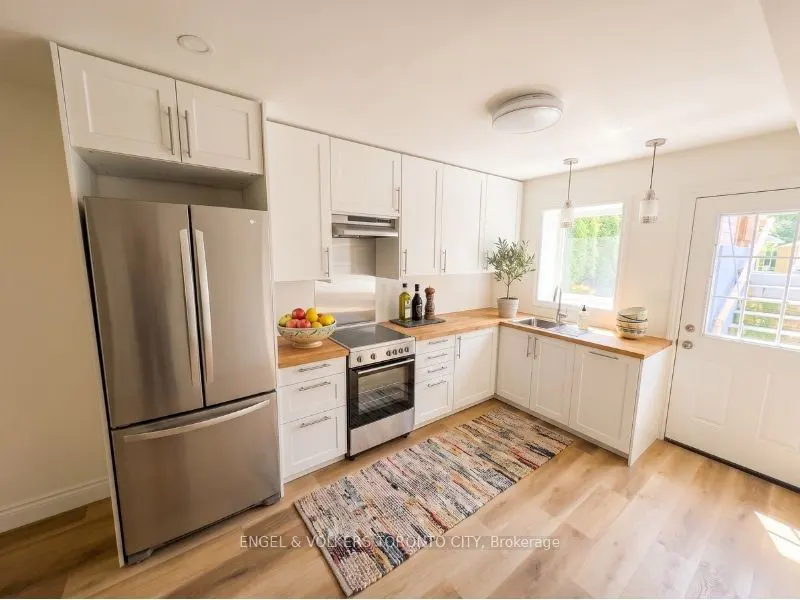 Bright kitchen with white cabinets, wood countertops, stainless steel appliances, and a colorful runner rug on wood floors.