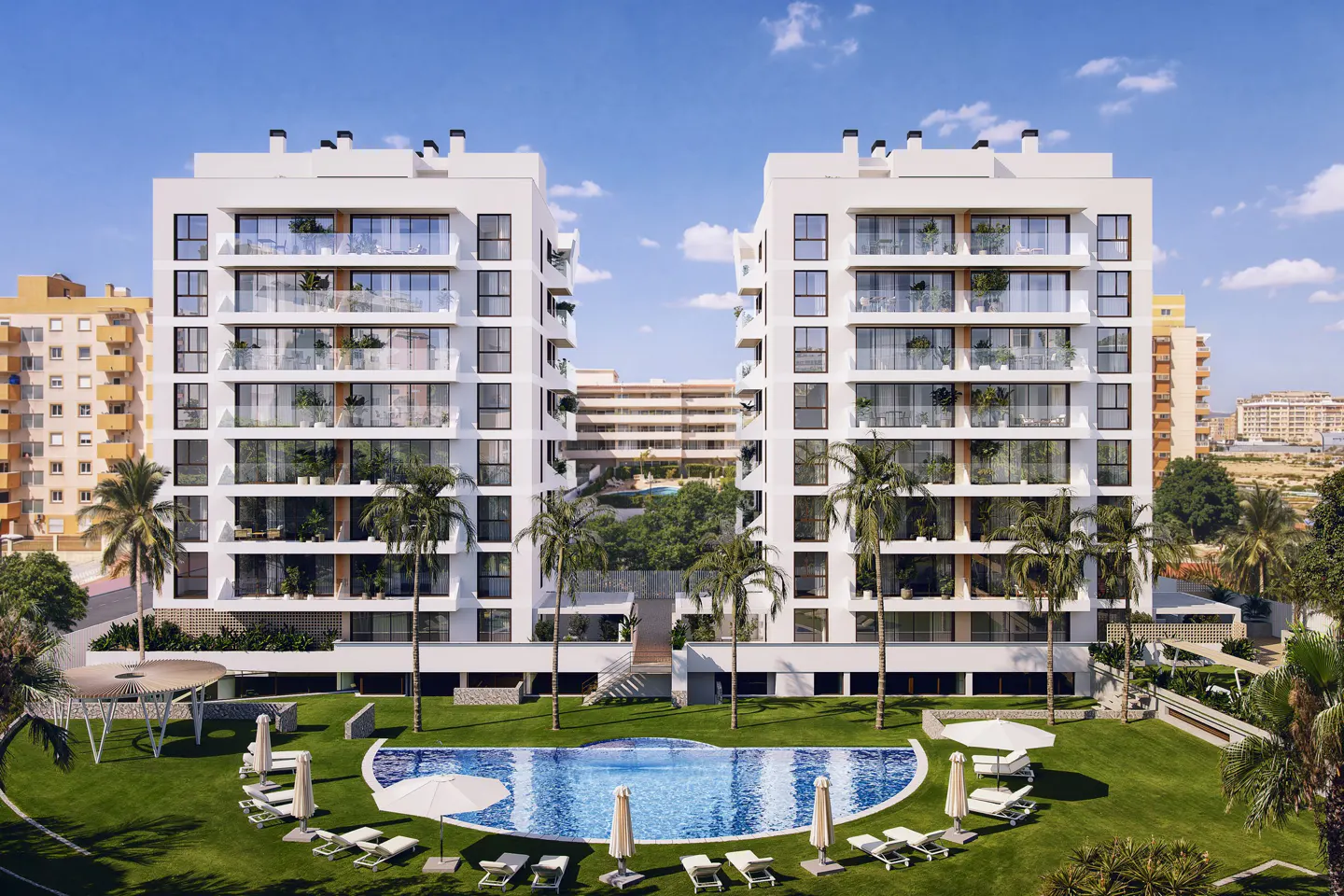 Exterior view of two modern white apartment buildings with balconies, a pool, palm trees, and lounge chairs on a sunny day.