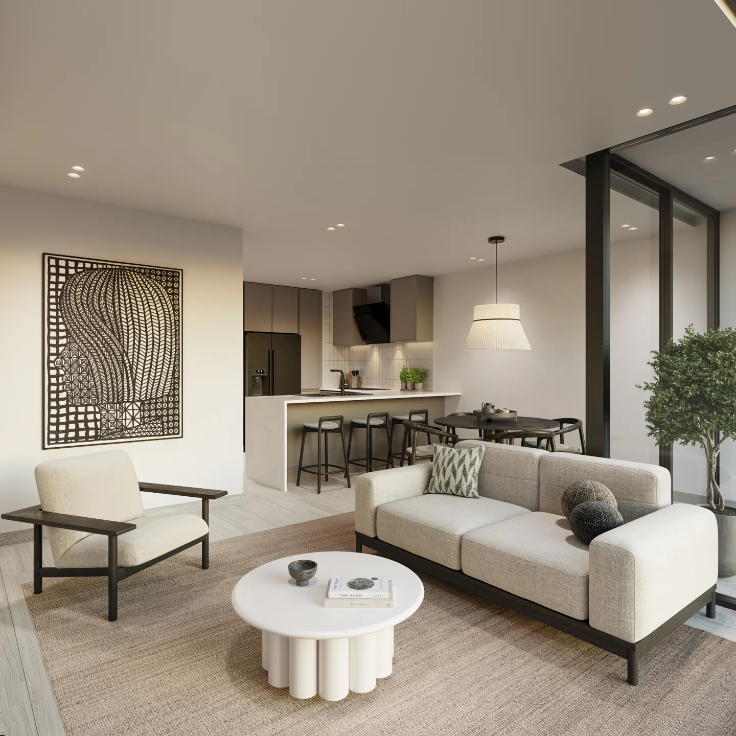 Open-concept living space with a beige sofa, white armchair, and round table on a tan rug. Kitchen island with stools and black and white art.