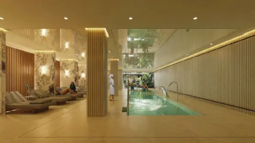 Indoor spa with a pool, lounge chairs, and people relaxing. The walls are marble and wood.