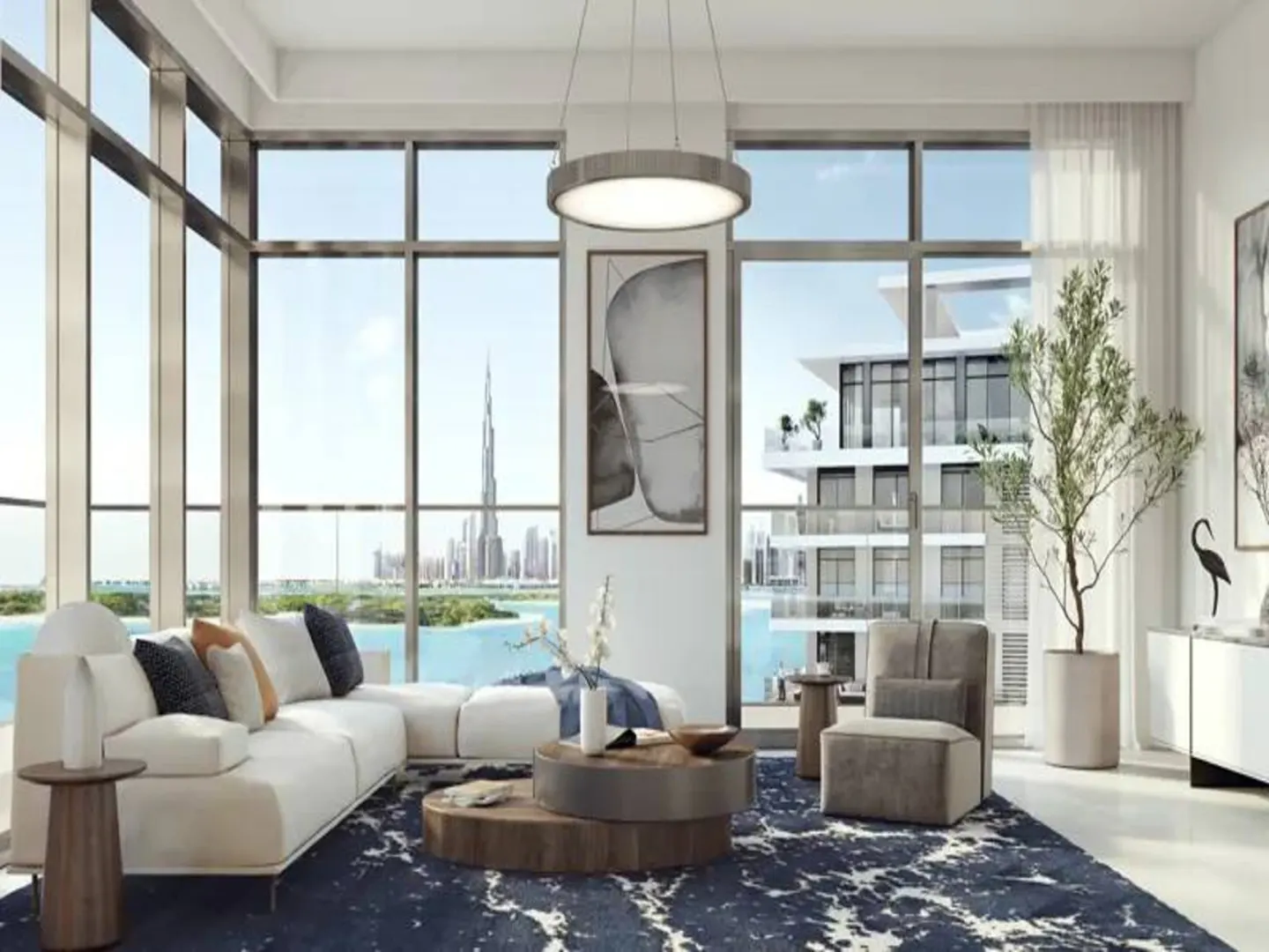 Bright living room with floor-to-ceiling windows overlooking Dubai skyline. White sectional sofa, round coffee tables, and blue patterned rug.