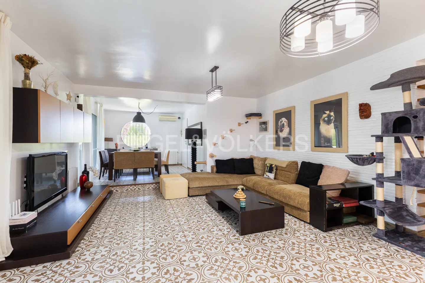 A bright living room with a brown sectional sofa, patterned tile floor, and a cat tree.