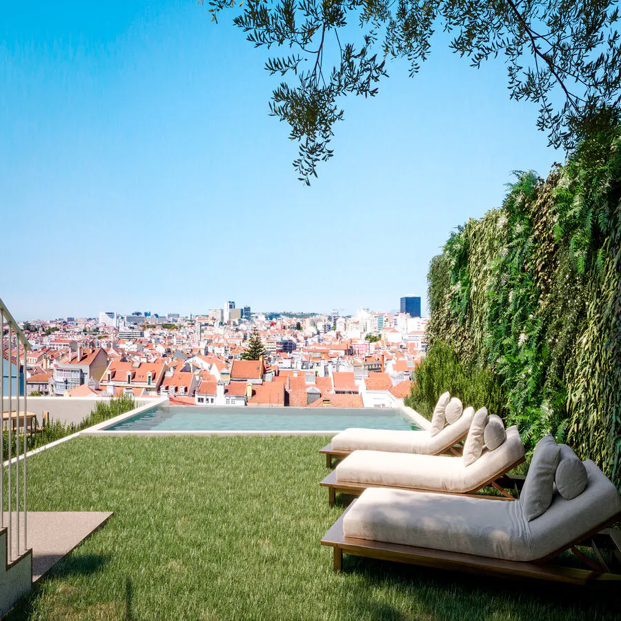 Three lounge chairs on a grassy terrace overlooking a city with red-tiled roofs and a vertical garden wall.