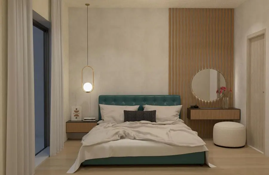 Bedroom with a teal bed, white linens, and a dark pillow. A gold pendant light hangs near a nightstand. A vanity with a round mirror is on the right.