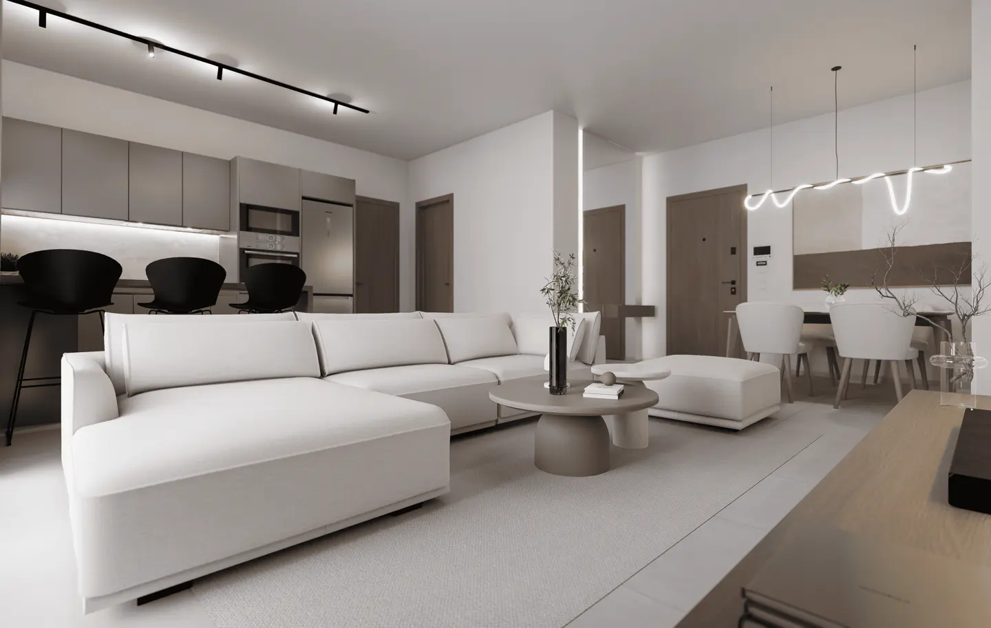 Open-concept living space with a white sectional sofa, round coffee table, and dining area with white chairs. Kitchen with gray cabinets and black bar stools.