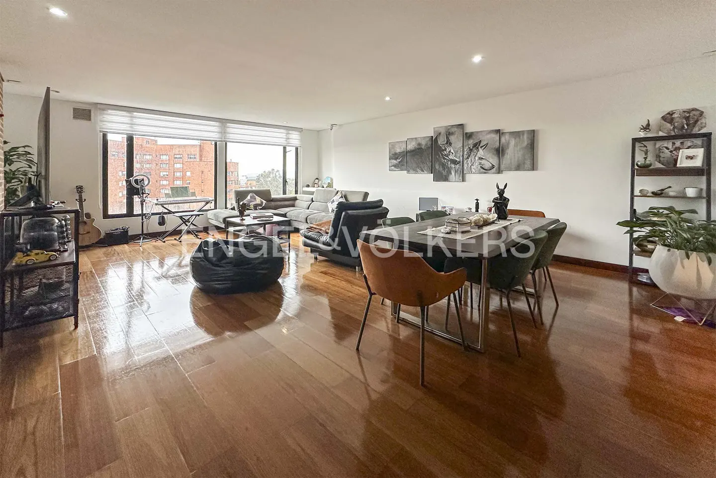 Bright, open-concept living and dining area with hardwood floors, large windows, and modern furniture.