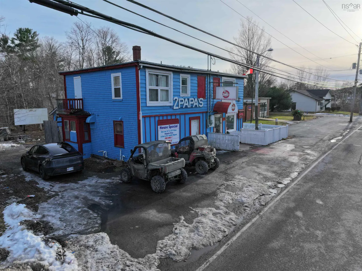 Exterior of "2 Papas" restaurant, a blue building with red trim, with ATVs parked in front. A black car is parked to the side.