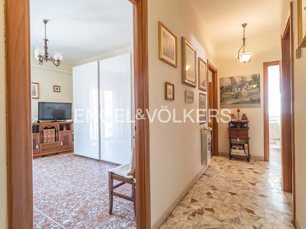 A view of a home's interior, showcasing a living room with a TV and a hallway adorned with framed pictures.