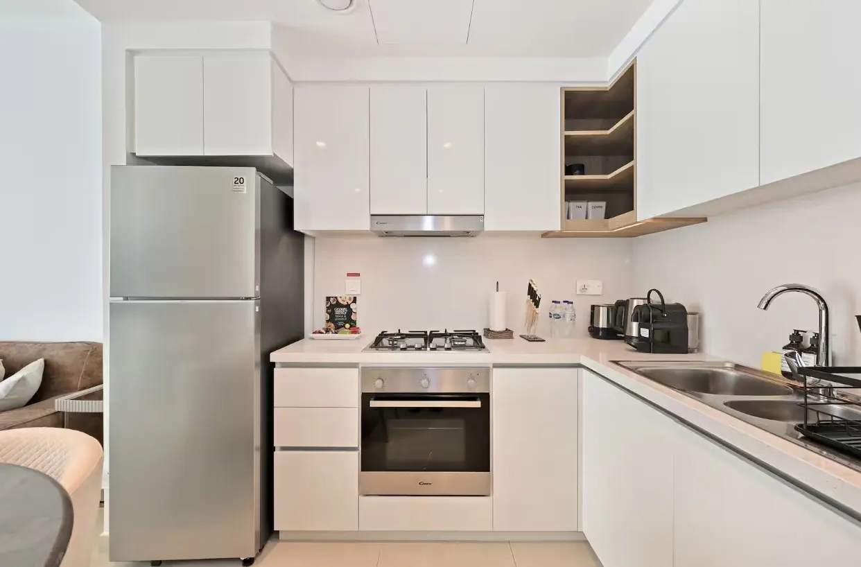 Bright, modern kitchen with white cabinets, stainless steel appliances, and a gas stovetop. Open shelving adds warmth.
