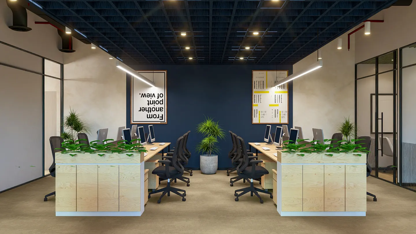 Office space with desks, computers, and plants. A dark blue wall is in the background with framed posters.