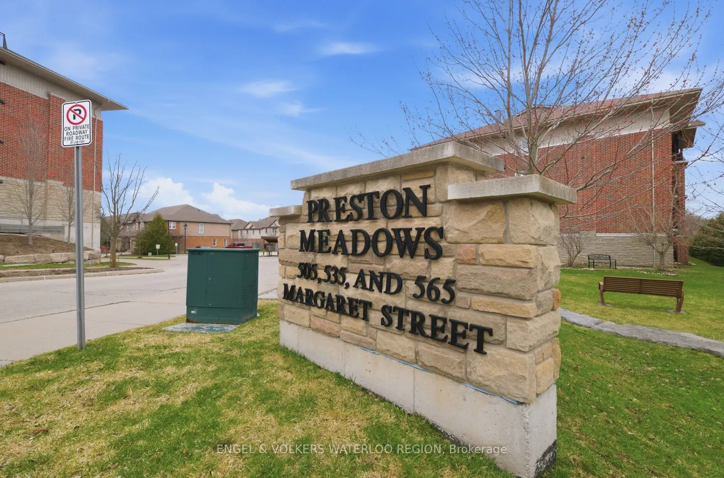 Stone sign reading "Preston Meadows, 505, 535, and 565 Margaret Street" on a grassy lawn with brick buildings in the background.