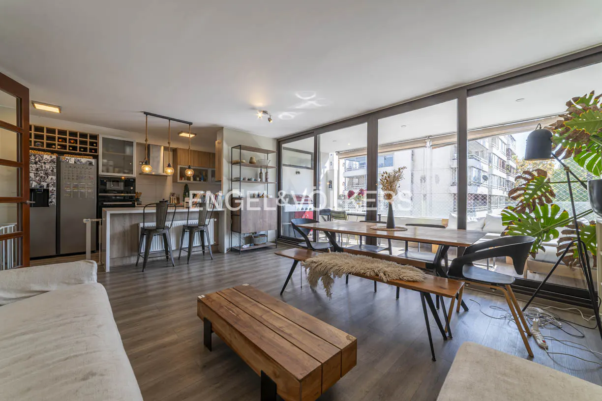 Open-concept living space with wood floors, a dining table, and a kitchen with bar stools. Large windows offer city views.