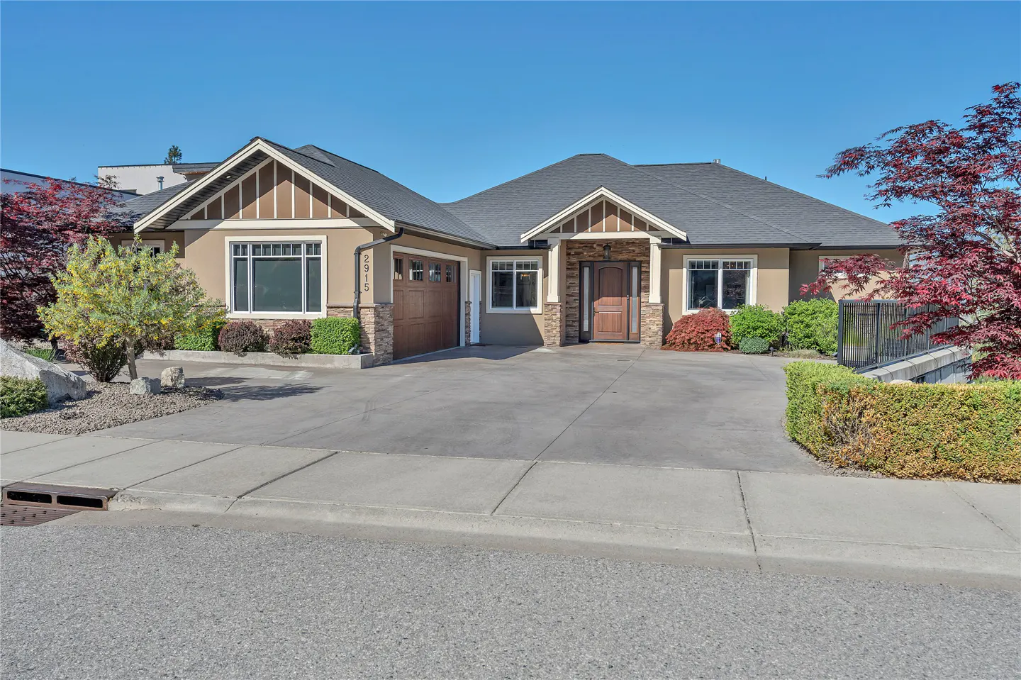 Front exterior of a tan single-story home with a gray roof, brown garage door, and a concrete driveway.
