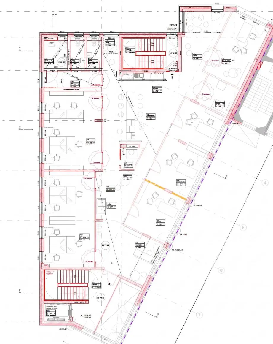 Blueprint of a building floor plan with red outlines, showing offices, stairs, and furniture layouts.