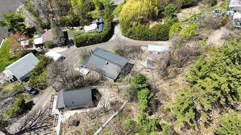 Aerial view of houses with dark roofs surrounded by trees and greenery.