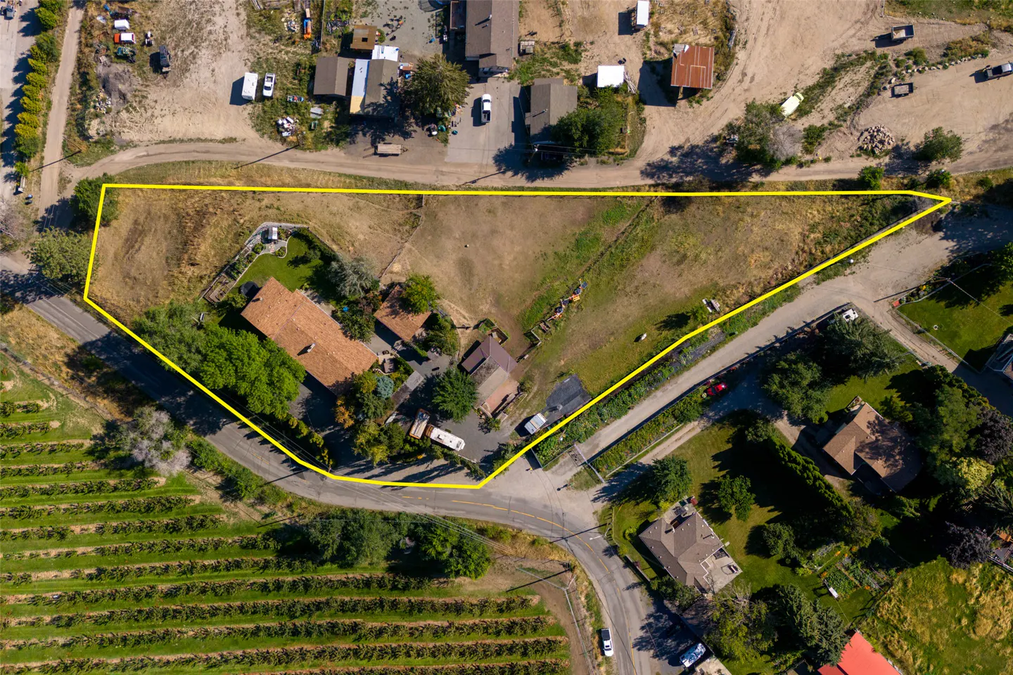 Aerial view of a property outlined in yellow, featuring a house, vineyard, and surrounding neighborhood.