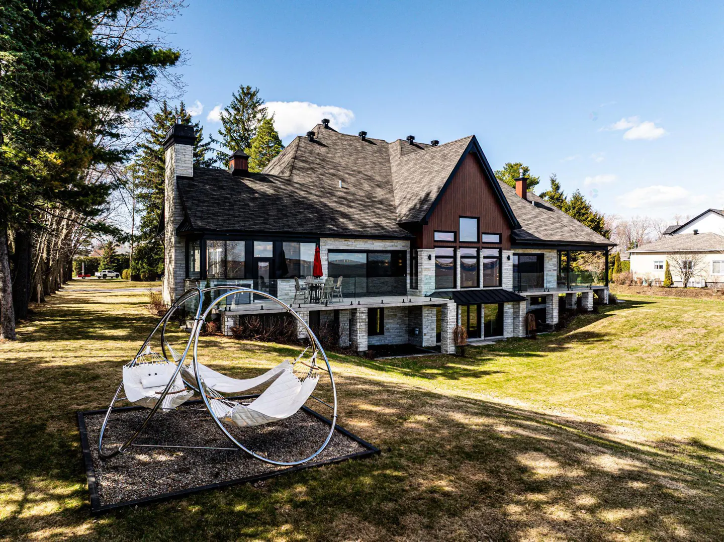 Back view of a two-story house with a deck, a hammock, and a green lawn.