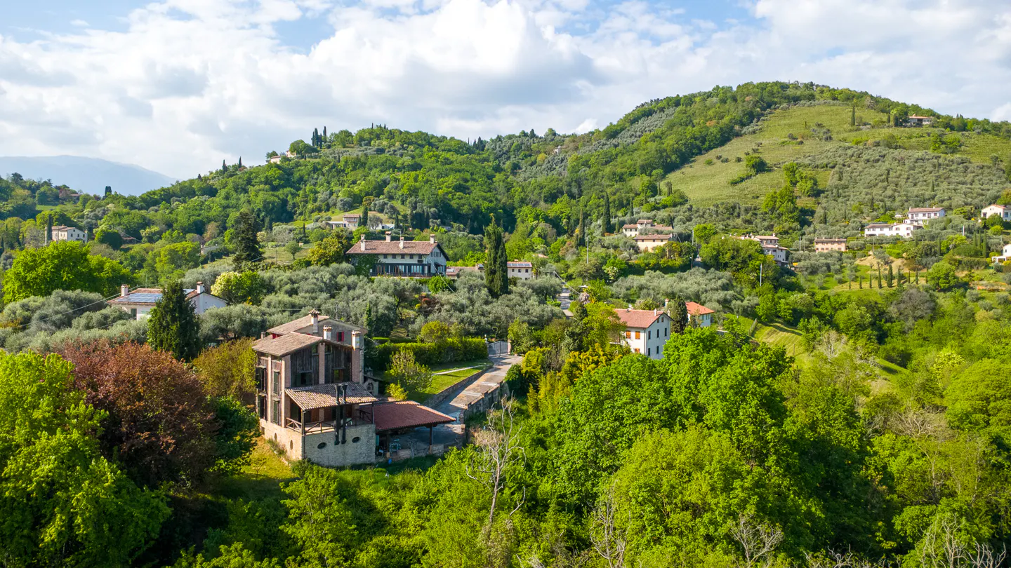 Hills covered in green trees and houses, with a stone house in the foreground.