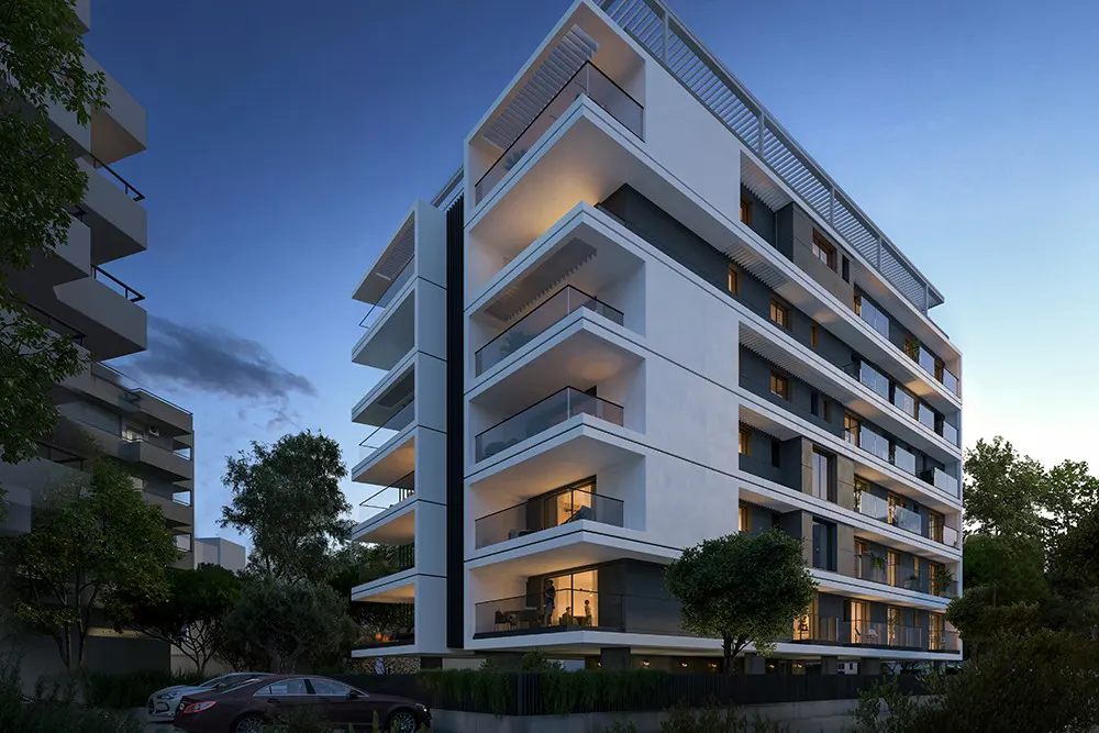 Modern white apartment building with glass balconies at dusk. Cars parked in front, surrounded by trees.