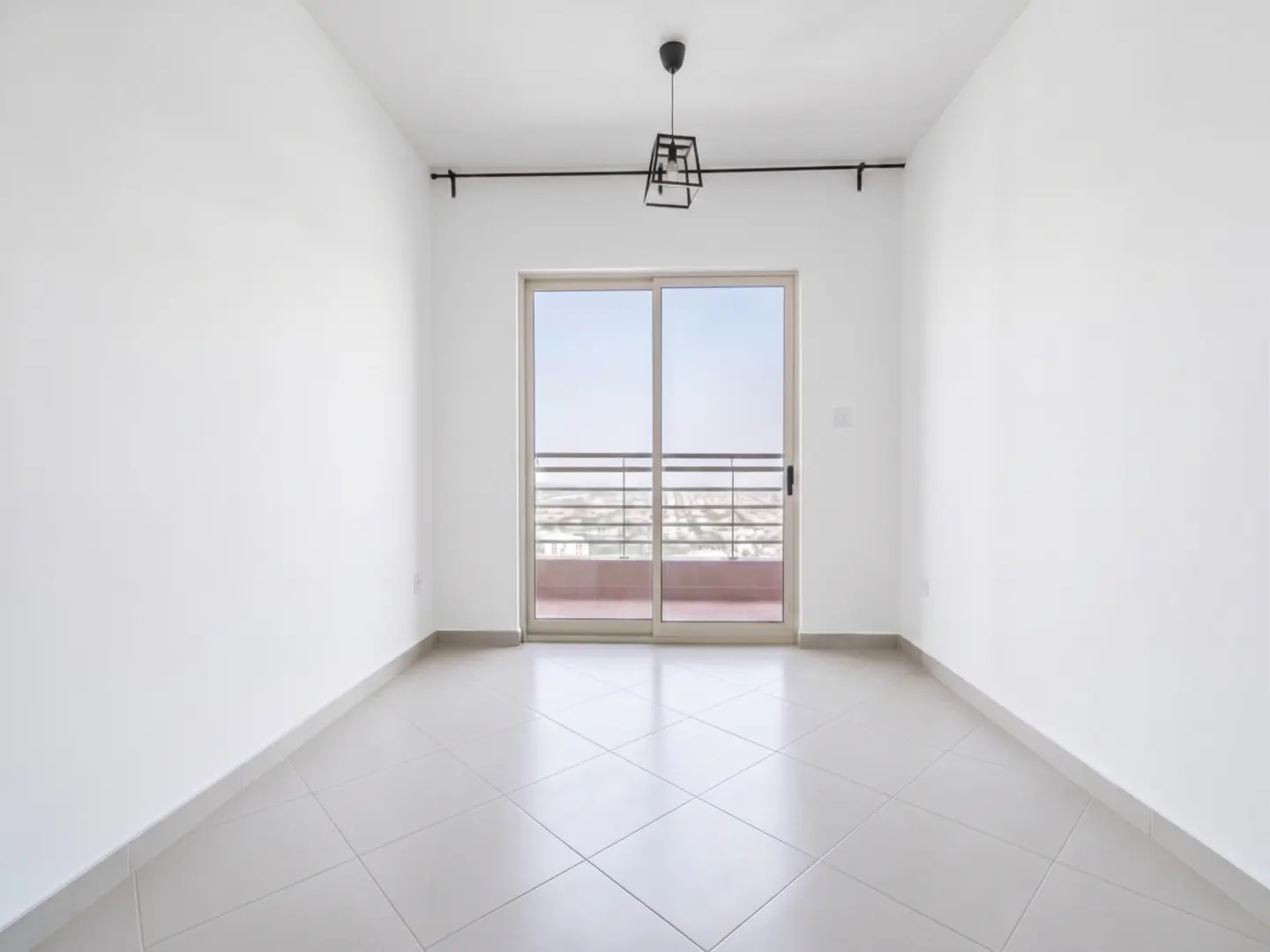 Empty room with white walls, tiled floor, and sliding glass doors to a balcony. A modern black light fixture hangs from the ceiling.