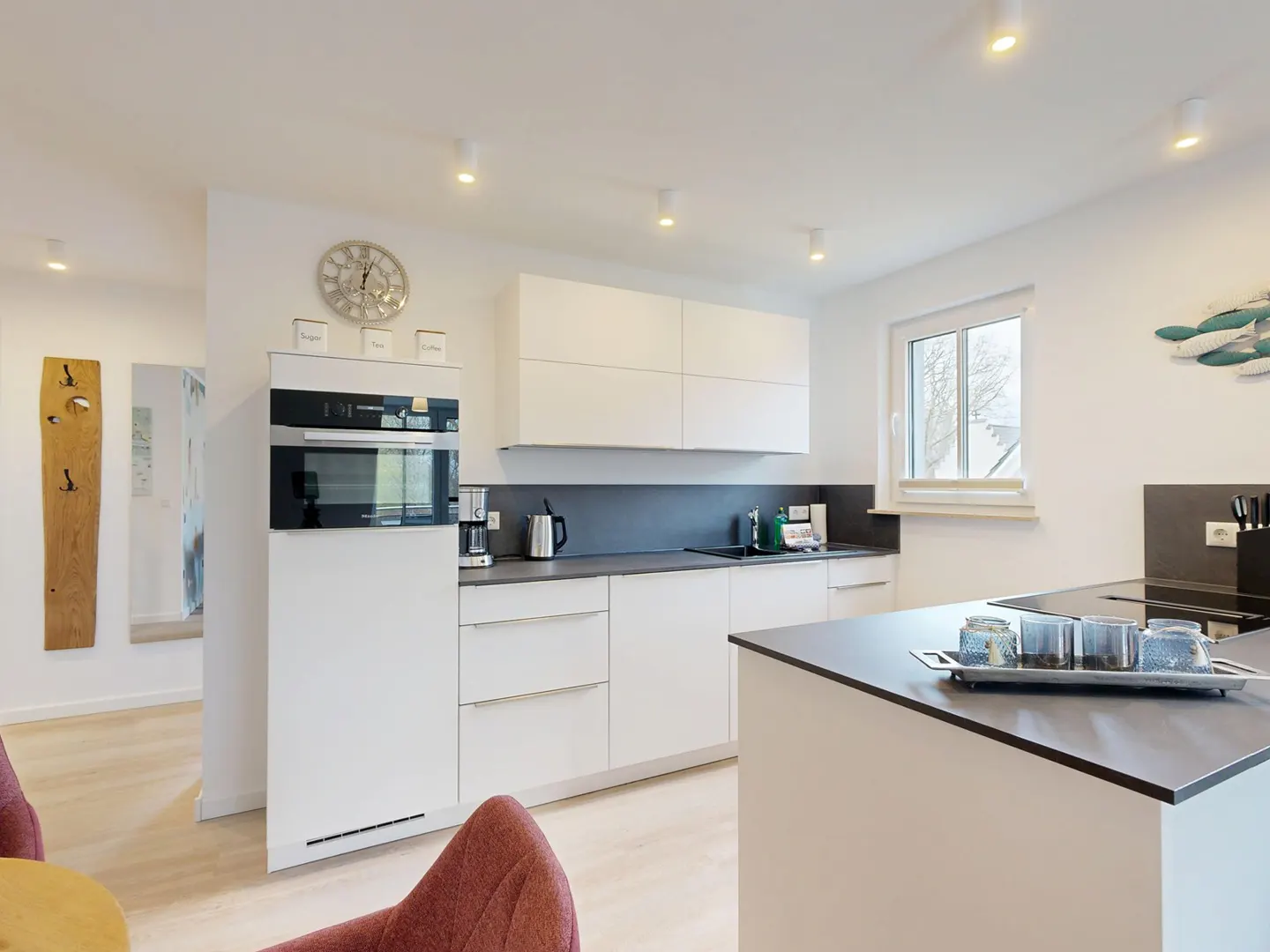 Bright kitchen with white cabinets, dark countertops, and stainless steel appliances. A kitchen island is in the foreground.