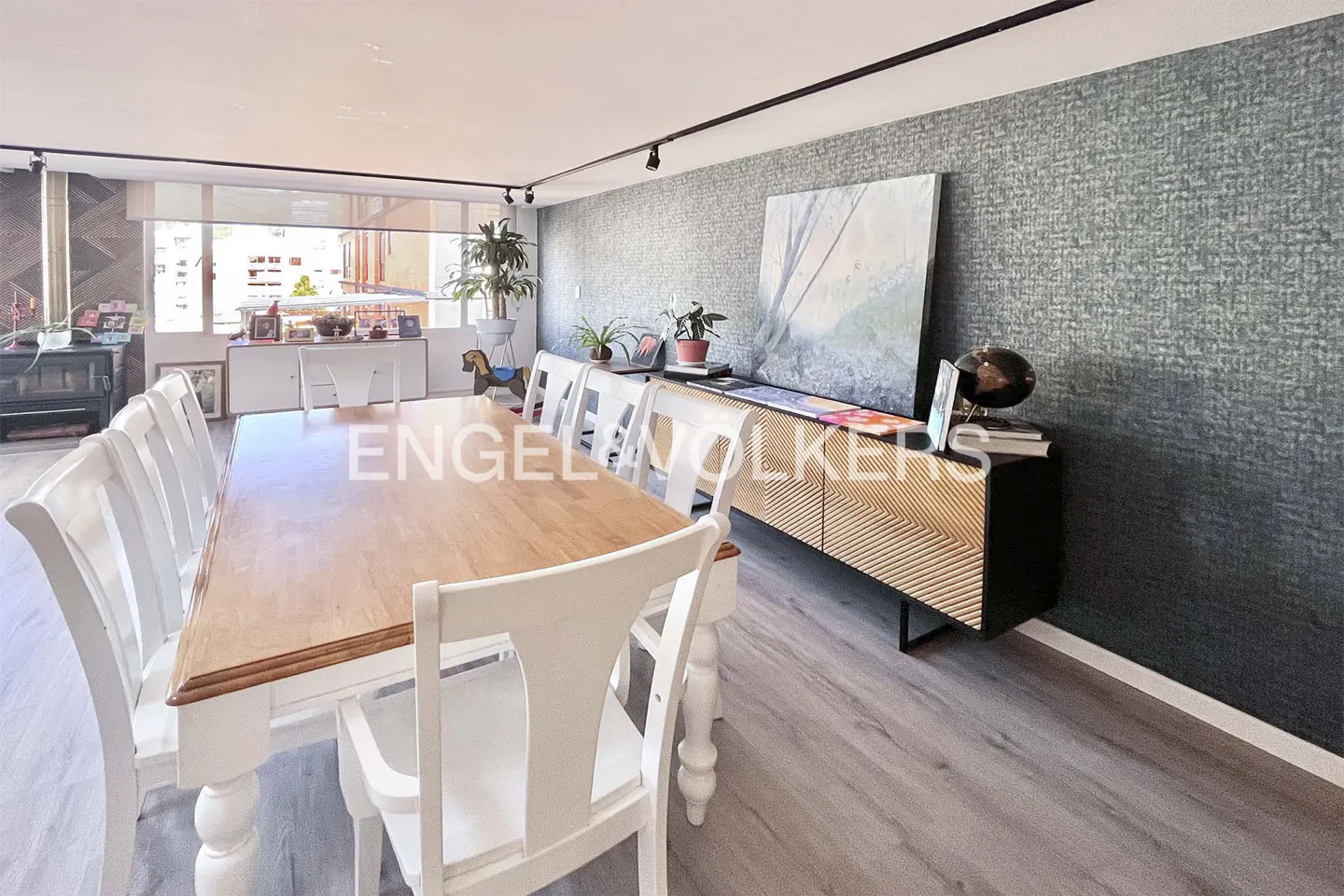 Dining room with a wooden table, white chairs, and a textured dark gray accent wall featuring a modern sideboard and art.