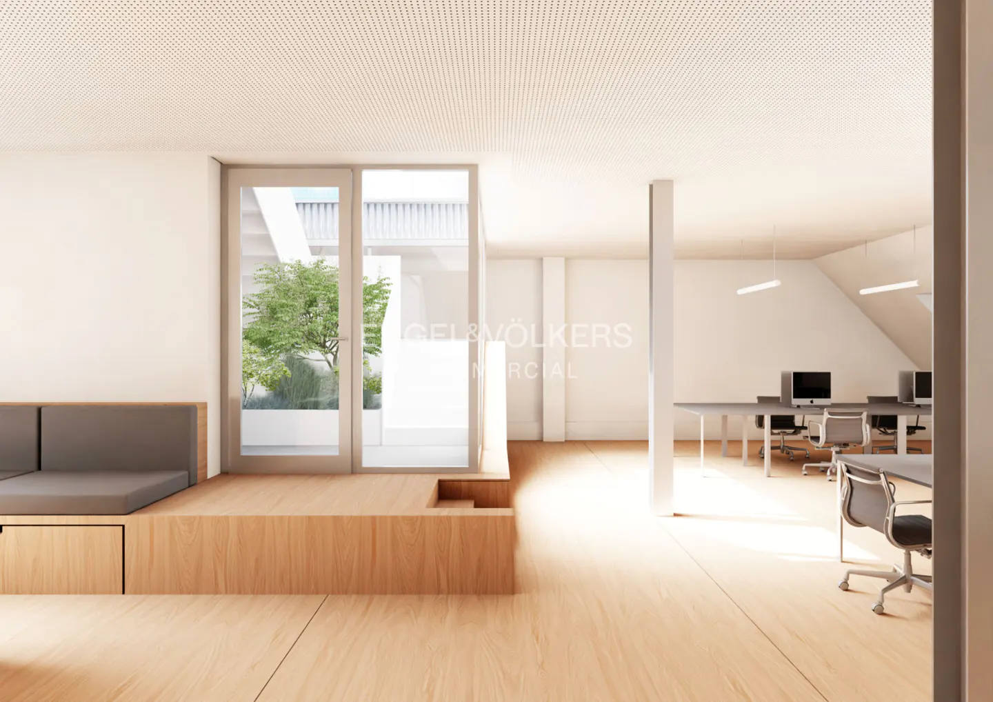 Bright office space with wood floors, a gray sofa, and desks with computers. A glass door leads to a courtyard with a tree.
